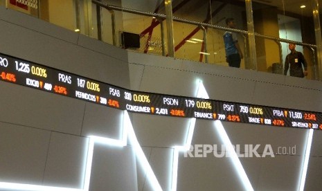 Pekerja melintas didekat layar pergerakan Indeks Harga Saham Gabungan (IHSG) di Gedung Bursa Efek Indonesia (BEI), Jakarta. ilustrasi