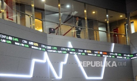 Pekerja melintas disamping layar pergerakan Indeks Harga Saham Gabungan (IHSG), Gedung Bursa Efek Indonesia (BEI) Jakarta, Selasa (18/4). 