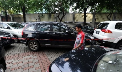 Pekerja melintas pada mobil sitaan yang tersegel di halaman kantor Komisi Pemberantasan Korupsi (KPK), Jakarta, Selasa (4/2). KPK kembali menyita lima mobil milik adik Gubernur Banten Ratu Atut Chosiyah, Tubagus Chaeri Wardana atau Wawan. terkait dugaan ti