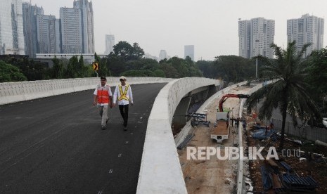 Pekerja melintas saat dilakukannya rangkaian uji coba Simpang Susun Semanggi di kawasan Semanggi, Jakarta, Kamis (13/7). 