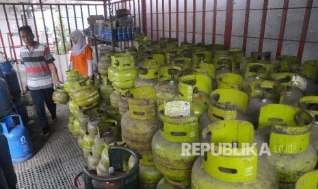  Pekerja mellayani pembeli gas elpiji tiga kilo di tempat penjualan gas di Jakarta, Ahad (2/4). 