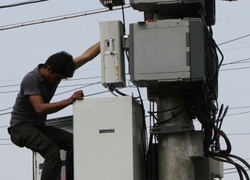 Pekerja memasang alat Remote Radio Unit (RRU) pada menara Base Transmitter System (BTS).