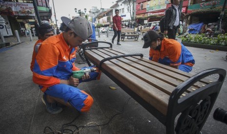 Pekerja memasang pembatas duduk bangku taman di kawasan pedestrian Malioboro, DI Yogyakarta, Senin (31/1).