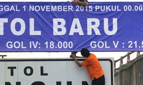 Pekerja memasang pengumuman penyesuaian tarif di pintu tol dalam kota, Jakarta, Sabtu (31/10). 