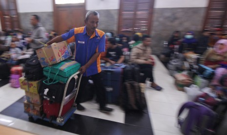 Pekerja membawa barang bawaan penumpang kereta api di Stasiun Gubeng Surabaya, Jawa Timur, Kamis (30/5/2019).