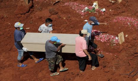 Pekerja membawa peti mati untuk dimakamkan 