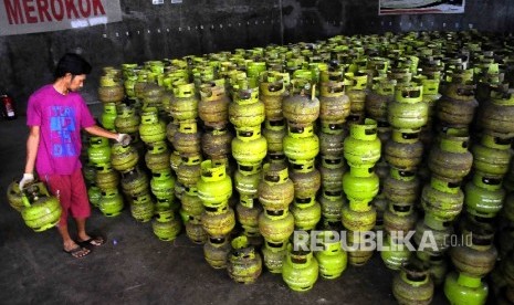 Pekerja membawa tabung gas elpiji tiga kilogram (gas melon) untuk dipindahkan ke truk pengangkut gas di agen penjualan gas, Mampang, Jakarta, Senin (31/10). 