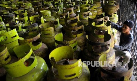 Pekerja membawa tabung gas elpiji tiga kilogram (gas melon) untuk dipindahkan ke truk pengangkut gas di agen penjualan gas, Mampang, Jakarta, Senin (31/10).