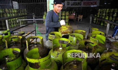 Pekerja membawa tabung gas elpiji tiga kilogram (gas melon) untuk dipindahkan ke truk pengangkut gas di agen penjualan gas, Mampang, Jakarta, Senin (31/10).