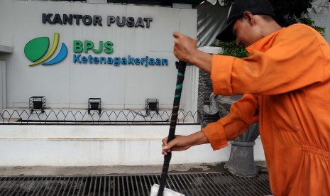 Pekerja membersihkan jalan didepan kantor Badan Penyelenggara Jaminan Kesehatan (BPJS) Ketenagakerjaan, Jakarta, Senin (6/7). 