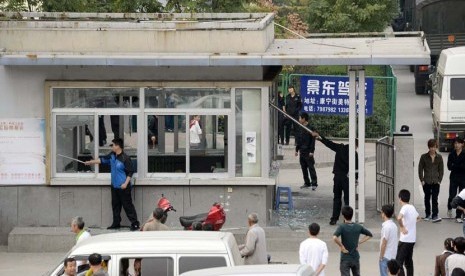  Pekerja membersihkan pecahan kaca dari jendela ruang keamanan yang pecah di pintu masuk pabrik Foxconn Tech-Industri Park di Taiyuan, provinsi Shanxi, Senin (24/9). (Reuters)