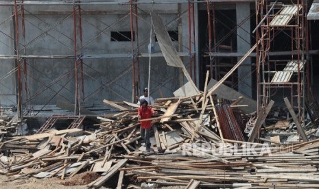 Pekerja membersihkan sisa kayu pada pembangunan Rusun yang dihentikan di kawasan Marunda, Jakarta Utara, Ahad (9/10).