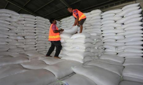 Pekerja membongkar muat karung berisi beras di gudang Perum Bulog.