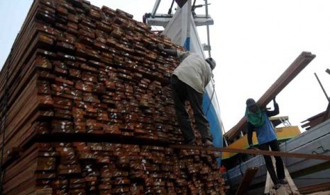 Pekerja membongkar muatan kayu.