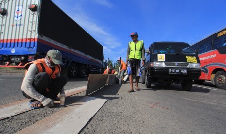 Pekerja membuat penutup putaran arah (U-turn) di Jalur Pantura Lohbener, Indramayu, Jawa Barat, Jumat (16/6). 