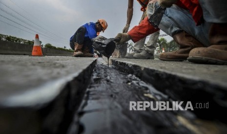  Pekerja memperbaiki jalan yang rusak (ilustrasi)