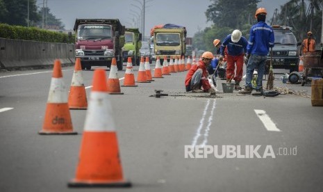  Pekerja memperbaiki jalan yang rusak di jalan tol Tangerang-Merak Kawasan Balaraja, Banten, Ahad (4/6).