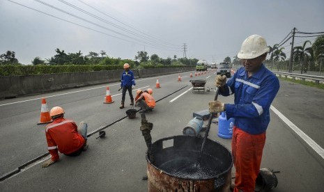 Pekerja memperbaiki jalan yang rusak di jalan tol Tangerang-Merak (ilustrasi)