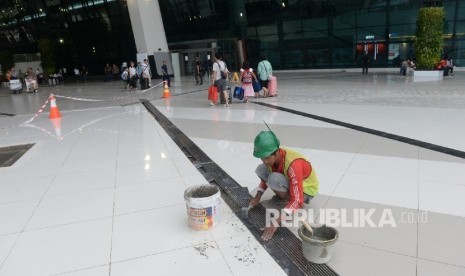 Pekerja memperbaiki lantai halaman Terminal 3 Ultimate pascabanjir, Bandara Soekarno-Hatta, Banten, Senin (15/8). (Republika/ Wihdan)