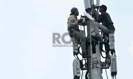  Pekerja memperbaiki menara pemancar telekomunikasi di Jakarta, Selasa (12/8). 