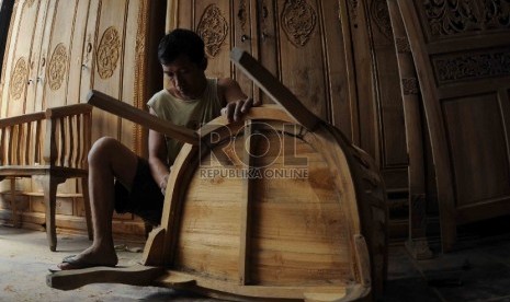 Pekerja mengamplas kursi kayu di tempat pembuatan furnitur dikawasan Manggarai, Jakarta, Senin (3/8).