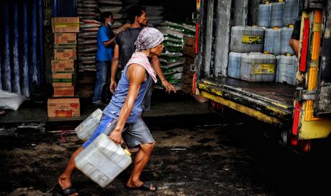 Pekerja mengangkat jerigen minyak di agen minyak curah.