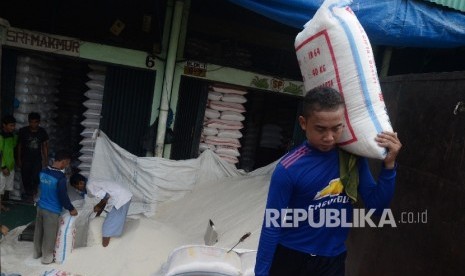 Pekerja mengangkat karung beras di Pasar Induk Beras Cipinang, Jakarta Timur, Kamis (13/4).