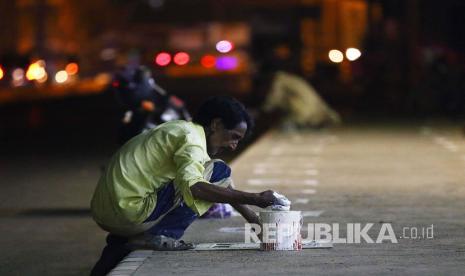 Pekerja mengecat tanda untuk menjaga jarak sosial di luar tempat perbelanjaan di Karachi, Pakistan, Ahad (17/5). Pakistan mencatat kasus kematian akibat Covid-19 tertinggi dalam sehari.