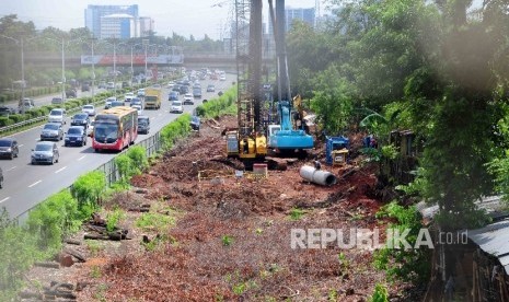 Pekerja menggunakan alat berat memasang tiang beton pada proyek pembangunan jalur kereta ringan atau Light Rail Transit (LRT) di sisi jalan Tol Cililitan, Jakarta, Ahad (17/4).  (Republika/Agung Supriyanto)