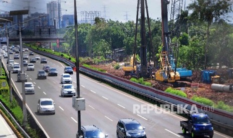 Pekerja menggunakan alat berat memasang tiang beton pada proyek pembangunan jalur kereta ringan atau Light Rail Transit (LRT) di sisi jalan Tol Cililitan, Jakarta, Ahad (17/4).  (Republika/Agung Supriyanto)