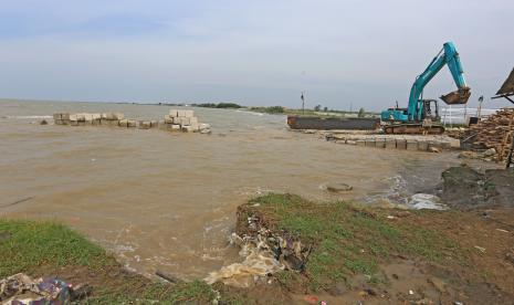 Pekerja menggunakan alat berat menyusun batu beton pemecah ombak di Pantai Dadap, Juntinyuat, Indramayu, Jawa Barat, Senin (18/7/2022). Kementerian Pekerjaan Umum dan Perumahan Rakyat (PUPR) melalui Balai Besar Wilayah Sungai Cimanuk-Cisanggarung (BBWS) melakukan penanganan abrasi pantai yang mengancam permukiman warga di daerah itu dengan membangun tanggul geobox sepanjang 4 km. 