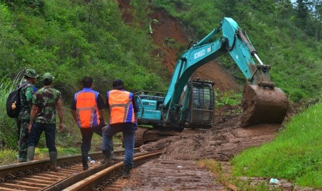 Pekerja menggunakan alat berat untuk membersihkan material tanah longsor yang menimbun jalur kereta api di KM 231+01 Malangbong, Kabupaten Garut, Jawa Barat, Kamis (23/11).