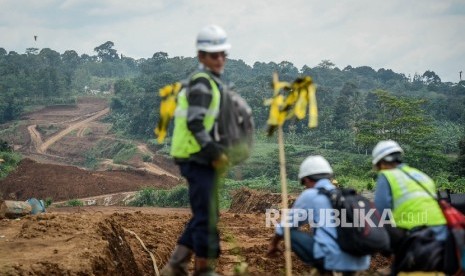 Pekerja menggunakan eskavator tengah menyelesaikan proyek pembangunan Jalan Tol 