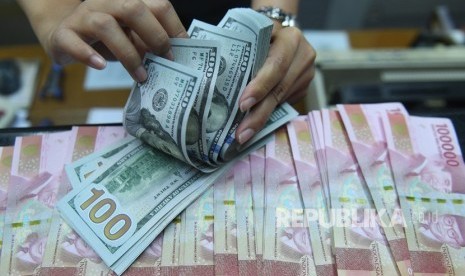 Pekerja menghitung uang dolar Amerika Serikat dan rupiah di sebuah tempat penukaran uang di Jakarta, Kamis (28/3).