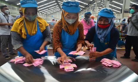 Pekerja menghitung uang Tunjangan Hari Raya (THR) yang diterimanya di pabrik rokok PT Djarum, Kudus, Jawa Tengah, Selasa (19/4/2022). Sebanyak 52.025 pekerja harian dan borongan yang tersebar di tujuh kota di perusahaan itu telah menerima uang THR guna membantu mereka dalam memenuhi kebutuhan keluarga selama bulan Ramadhan dan Idul Fitri. 