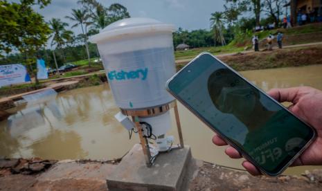 Pekerja mengoperasikan e-Fishery untuk memberi pakan ikan.