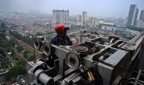  Pekerja mengunakan gondola saat melakukan perawatan gedung perkantoran di Sudirman, Jakarta, Senin (9/11).