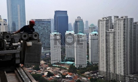 Pekerja mengunakan gondola saat melakukan perawatan gedung perkantoran di Sudirman, Jakarta, Senin (9/11).