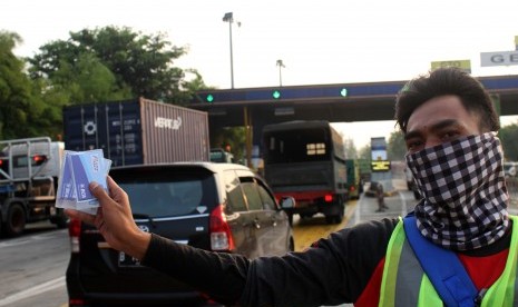 Pekerja menunjukkan kartu pembayaran elektronik tol (E-Toll) yang dijual di pintu gerbang Tol Cikunir, Bekasi, Jawa Barat.