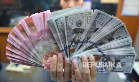 Pekerja menunjukkan uang Rupiah dan Dollar Amerika Serikat di sebuah tempat penukaran uang di Jakarta, Kamis (28/3/2019).