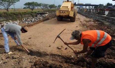 Pekerja menyelesaikan pekerjaan pelebaran lajur jalan pintu keluar-masuk gerbang tol Karawang Barat, di Karawang, Jawa Barat, Senin (9/11).