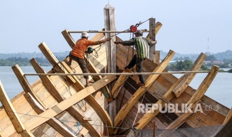 Pekerja menyelesaikan pembuatan kapal nelayan di pesisir kawasan Tempat Pendaratan Ikan Desa Pusong, Lhokseumawe, Aceh, Selasa (9/7/2019). 