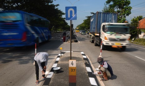 Pekerja menyelesaikan pengecatan pembatas jalan jalur Pantura Demak-Kudus, Jawa Tengah, Jumat (17/5/2019).