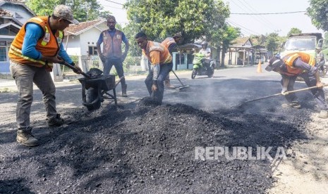 Pekerja menyelesaikan perbaikan jalan alternatif menuju jalur Pantura di jalan raya Cikalong - Cilamaya, Karawang, Jawa Barat (ilustrasi)