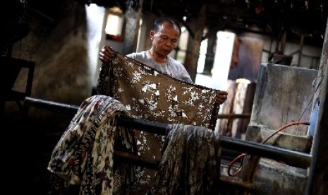 Pekerja menyelesaikan proses pewarnaan batik dengan bahan warna alami