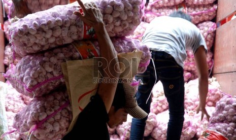  Pekerja menyusun bawang putih impor saat bongkar muat di Pasar Induk Kramat Jati,Jakarta,Senin (10/12).    (Republika/Prayogi)