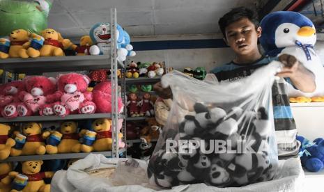 Pekerja merapikan boneka yang akan dikirim di kokao toys mart, Bekasi, Jawa Barat, Sabtu (18/9/2021). OJK memperluas akses keuangan melalui pembentukan skema KUR Klaster.