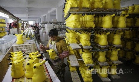 Pekerja mewarnai celengan berbentuk Picachu di sebuah pabrik di Provinsi Fujian, China.