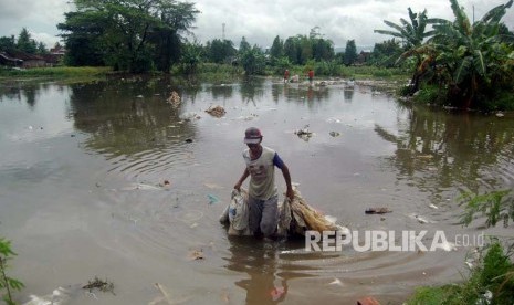 Pekerja pabrik pengolahan Plastik bekas di desa Timbulharjo, Kecamatan Sewon Bantul mengumpulkan sisa-sisa bahan siap olah yang hanyut terkena banjir Selasa (28/11). Selama dua hari banjir telah melumpuhkan sektor industri dan pendidikan di Bantul.