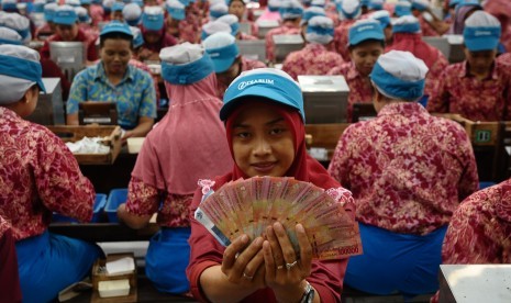 Pekerja pabrik rokok menunjukkan uang Tunjangan Hari Raya (THR) Lebaran di Kudus, Jawa Tengah, Kamis (15/6). 